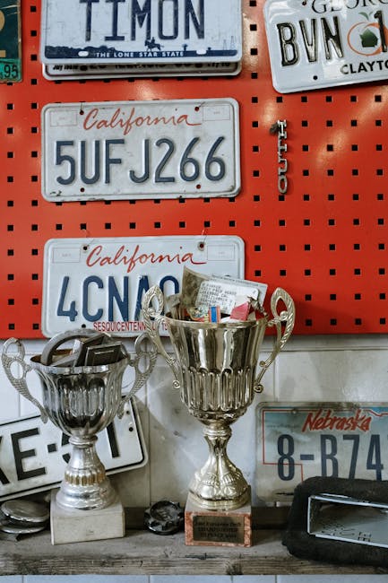 A collection of vintage license plates and shiny trophies on a workshop wall.