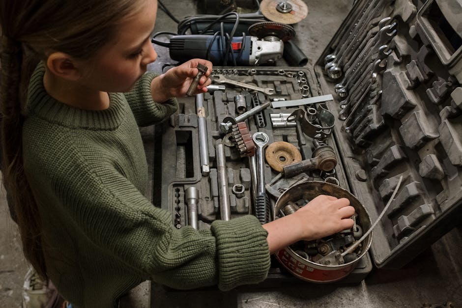 A young girl examines assorted tools and equipment in a garage workshop, depicting curiosity and hands-on learning.
